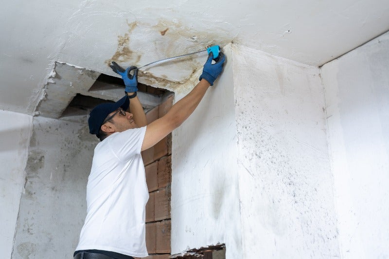 Technician inspecting ceiling water leak damage in Jacksonville, FL